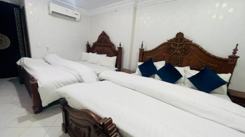 three beds in a room with white and blue pillows at Hotel New Mid City Multan in Multan
