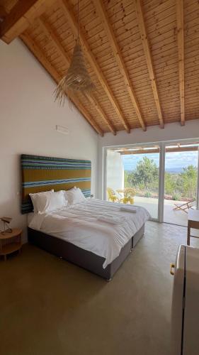 a bedroom with a large bed and a large window at Vale das Estrelas in São Teotónio