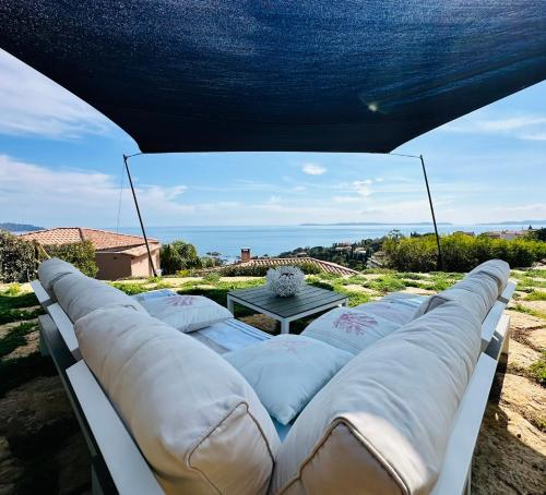un grupo de almohadas en un sofá bajo una tienda en La plage de Saint Clair à pied, en Le Lavandou