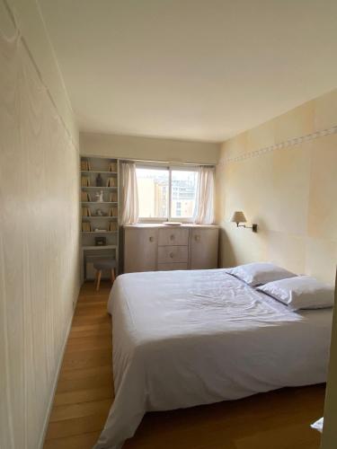 une chambre avec un lit blanc et une fenêtre dans l'établissement Appartement chaleureux au cours du 15eme, à Paris