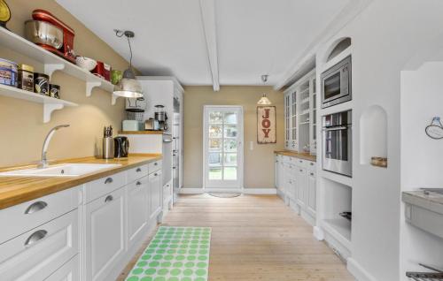 a kitchen with white cabinets and a green rug on the floor at 3 Bedroom Awesome Home In Bindslev in Bindslev