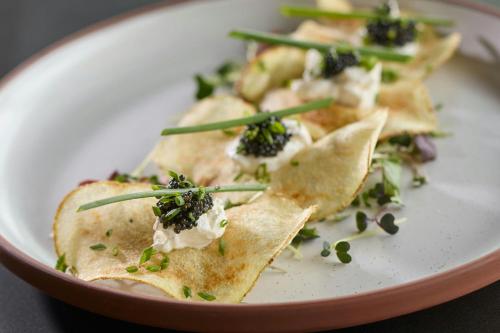 a plate of tortilla chips with broccoli and cheese at Hotel Celare, Cincinnati Midtown, a Tribute Portfolio Hotel in Cincinnati