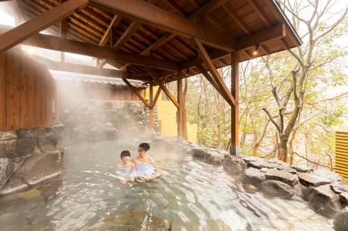 two children are sitting in a hot tub at Ooedo Onsen Monogatari Premium Yamanaka Grand Hotel in Kaga