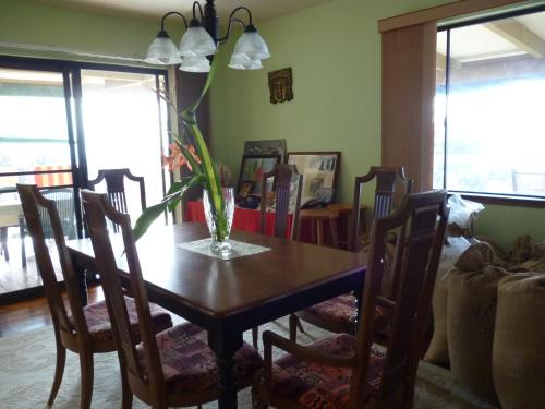 a dining room table with chairs and a vase on it at A Beautiful Edge of the World Bed & Breakfast in Captain Cook