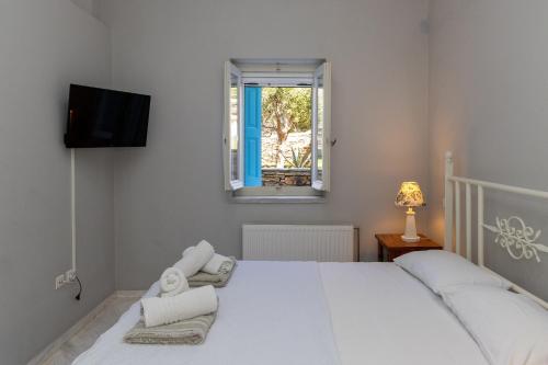 a bedroom with a white bed and a window at Villa Marble Tinos in Agios Fokas