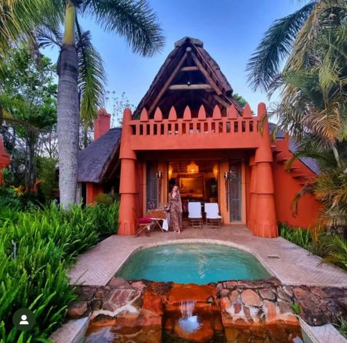 a woman standing in front of a house with a pool at Timamoon Lodge in Hazyview