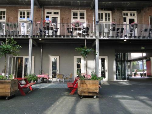 a building with tables and chairs and potted plants at LABnul50 self check-in hotel Groningen in Groningen