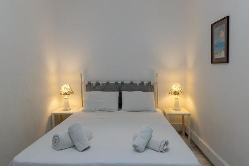 a bedroom with a large white bed with two lamps at Villa Marble Tinos in Agios Fokas