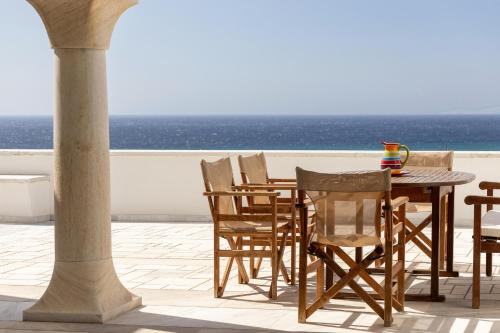 a table and chairs on a balcony with the ocean at Villa Marble Tinos in Agios Fokas