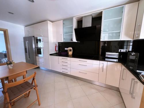 a kitchen with white cabinets and a table and a microwave at Moradia Fantástica com Piscina a 5 min da Praia in Monte Gordo