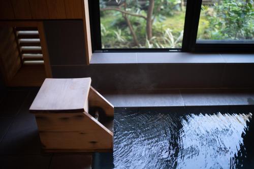 a room with a bench next to a pond at Fujinohana Hotel in Kirishima
