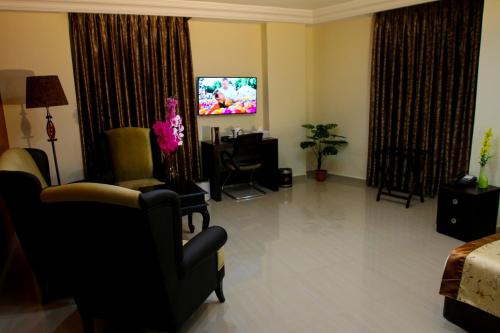 a living room with a tv and a couch and chairs at Queen Plaza Hotel in Hebron