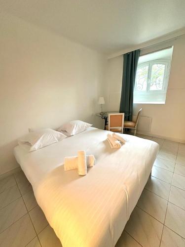 une chambre avec un grand lit blanc avec deux serviettes dessus dans l'établissement Spacious Apartment - High Standing Residence, à Cannes