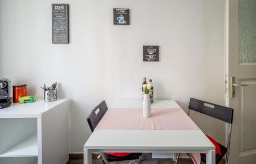 a white table with two chairs and a vase with wine bottles at Ruben's Apartments in Stuttgart