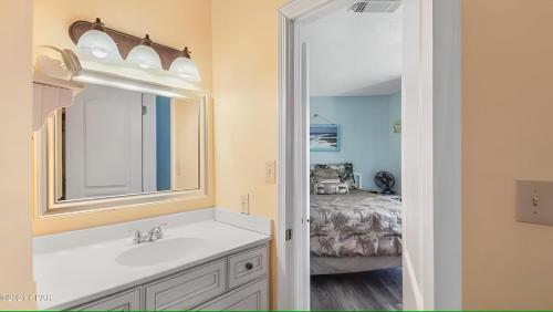 a bathroom with a sink and a mirror and a bedroom at Across the Street from beach with 2 pools in Panama City Beach