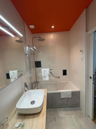 a bathroom with a sink and a bath tub at Hôtel Moderna in Cherbourg en Cotentin