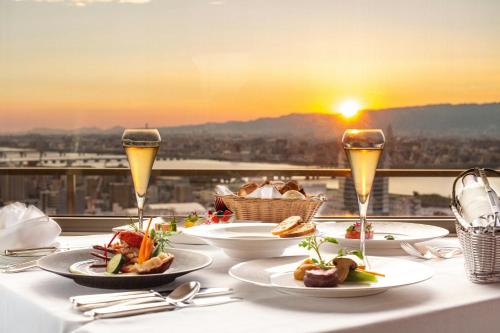 a table with plates of food and two glasses of wine at The Westin Osaka in Osaka