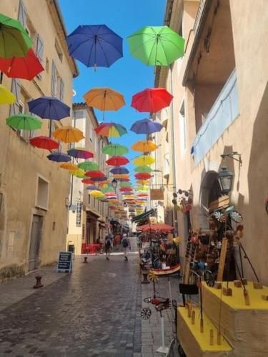 Une bande de parapluies colorés suspendus au-dessus d'une rue dans l'établissement Agreable maison anduzienne au coeur du village, à Anduze