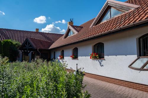 a white house with red roofs and flowers in windows at Siedlisko Leszczewek in Leszczewek