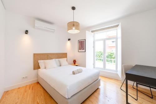 a white bedroom with a bed and a desk at Sunny Lisbon Apartments by Soulplaces in Lisbon