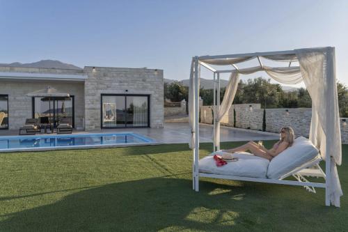 a woman laying on a bed next to a pool at Villa Lux Solis - With 2 Pools in Khoumérion