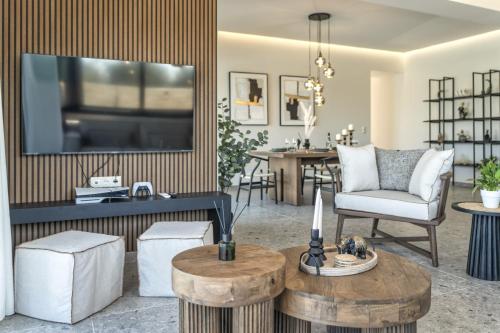 a living room with a tv on a wall with a table at Villa Lux Solis - With 2 Pools in Khoumérion