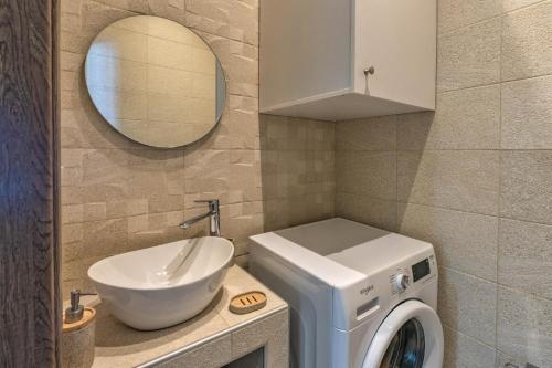 a bathroom with a sink and a washing machine at Villa Lux Solis - With 2 Pools in Khoumérion
