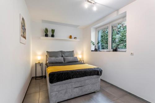a bed in a white room with two windows at Tua Casa - Souterrain Appartment in Lippstadt