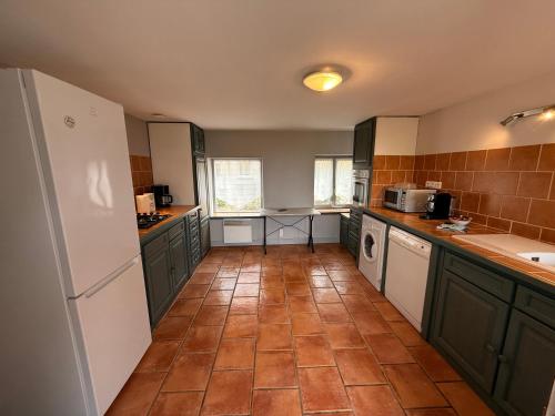 Il comprend une cuisine avec des placards verts et du carrelage. dans l'établissement Maison Familiale au milieu des vignes-Les Huards, à Cour-Cheverny