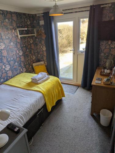 a bedroom with a bed with a yellow blanket and a window at Seals Bacton in Bacton