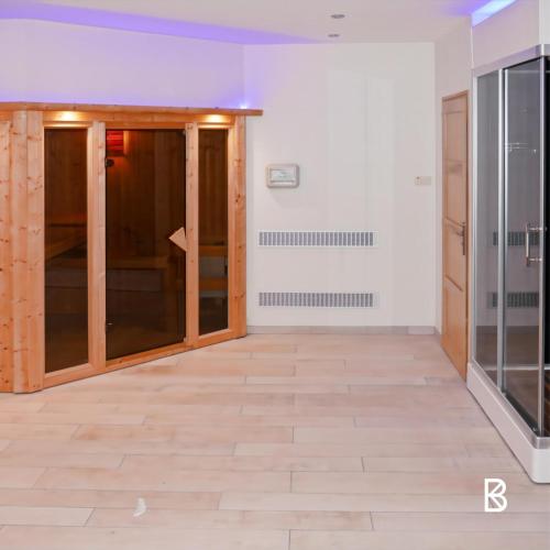 an empty room with glass doors and wood floors at LÉchappée ZAisne jacuzzi et sauna in Saint-Quentin