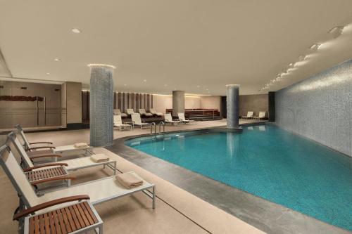 a large swimming pool in a hotel lobby with chairs at Sheraton Istanbul Levent in Istanbul