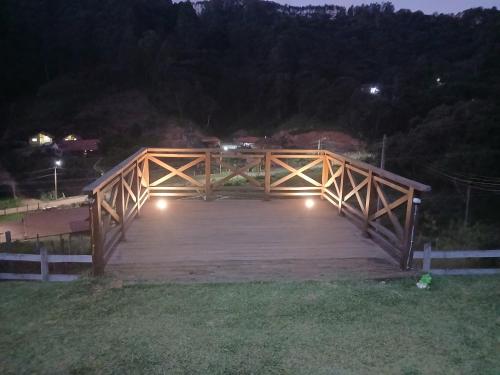 a wooden bridge at night with lights on it at Chalé monte verde com hidromassagem in Camanducaia