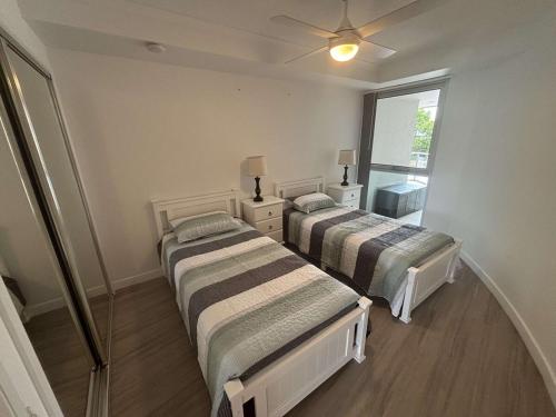 two beds in a room with a window at Seaside Sovereign Retreat in Caloundra