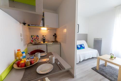- une petite cuisine avec une table et des fruits dans l'établissement Sphinx Résidences - Les Doges / Le Rialto, à Caen