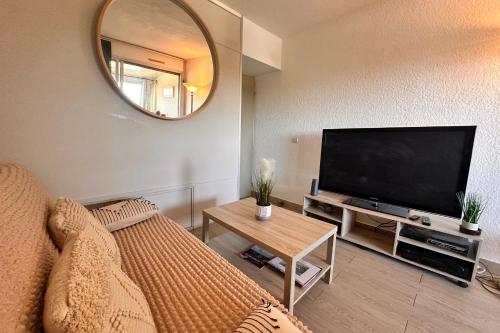 un salon avec un canapé et une télévision à écran plat dans l'établissement Le Quai aux Fleurs - Résidence avec piscine proche de la mer, au Grau-du-Roi