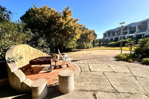 un banc installé sur une terrasse en briques à côté d'un bâtiment dans l'établissement Le Quai aux Fleurs - Résidence avec piscine proche de la mer, au Grau-du-Roi