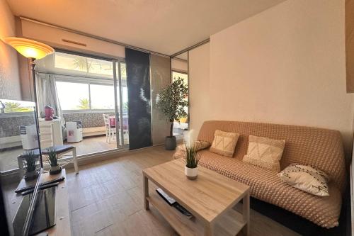 un salon avec un canapé et une table dans l'établissement Le Quai aux Fleurs - Résidence avec piscine proche de la mer, au Grau-du-Roi