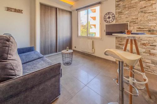 un salon avec un canapé et une horloge au mur dans l'établissement Contemporary 2P Studio Just Steps from the Beach, à Cagnes-sur-Mer