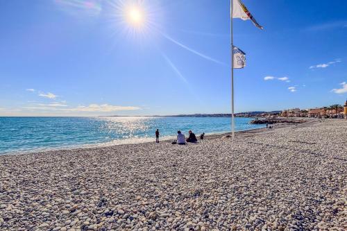 un groupe de personnes assises sur une plage avec drapeau dans l'établissement Contemporary 2P Studio Just Steps from the Beach, à Cagnes-sur-Mer