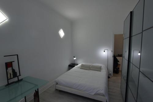 une chambre blanche avec un lit et une table en verre dans l'établissement First floor apartment fully renovated, à Antibes