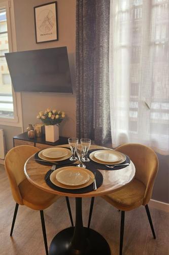 une table avec des assiettes et des verres à vin dessus dans l'établissement Le Deauvillais Studio en plein cœur de Deauville, à Deauville