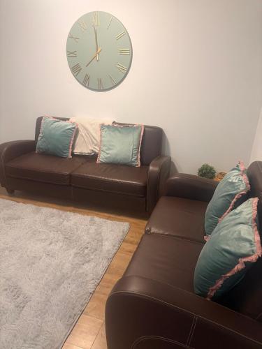 a living room with two couches and a clock on the wall at Family and Contractor 4BR All En-suite Apt with Free WiFi and Parking in Warwick