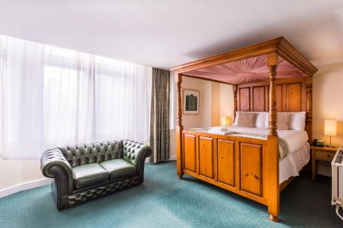 a bedroom with a canopy bed and a chair at The Gardens Hotel in Manchester