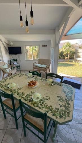 une table à manger avec des chaises et une table avec une assiette de nourriture dans l'établissement Mobile home en bord de mer, à Bretteville-sur-Ay