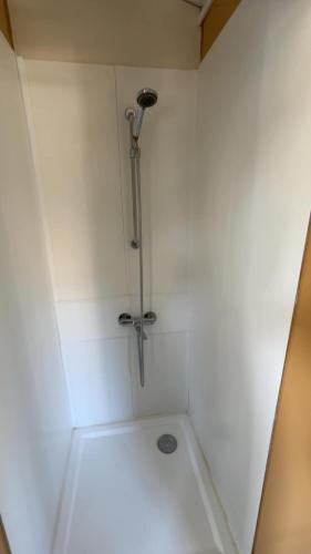 - une douche blanche avec pommeau dans l'établissement Mobile home en bord de mer, à Bretteville-sur-Ay