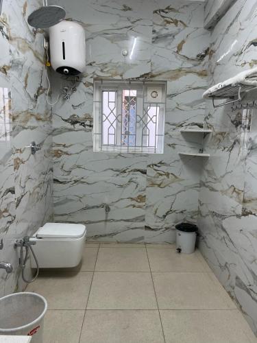a stone bathroom with a toilet and a window at Ahika Stays in Bengaluru