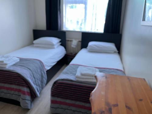 a room with two beds and a wooden table at The Coach House in Feevaghmore