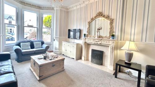 a living room with a fireplace and a mirror at Arvon House in Llandudno