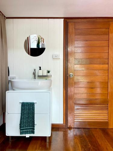a bathroom with a sink and a wooden door at Anna River Home A3 in Ban Khlong Si